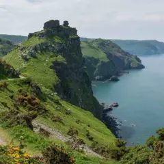 A winding path hugs a grassy cliff overlooking the sea. This is the salt path, a scenic route with rugged beauty.