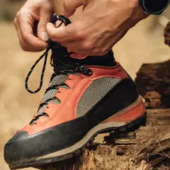 Lacing up sturdy resole hiking boots for an adventure. The orange and black design promises grip and support on any trail.