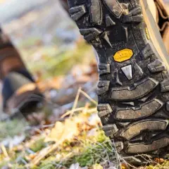 Close-up of a hiking boot sole on a forest floor. Learn how to break in hiking boots for comfortable adventures.