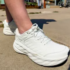 White walking shoes on a sidewalk. The question of whether walking shoes should be a size bigger is on many minds.