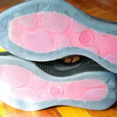 Soles of two black sneakers with pink grip zones and clear rubber outsoles. These shoes are designed to maximize traction, offering a great solution for how to make shoes more grippy.