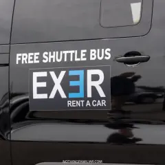 Black shuttle bus with "EXER RENT A CAR" logo. Considering whether to rent a car in Athens? This shuttle might be a good option.