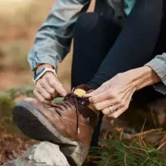 A person demonstrates how to lace boots, preparing for an outdoor adventure.