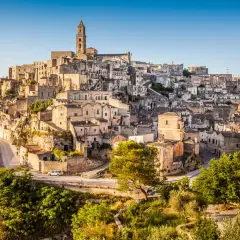 A panoramic view of Matera, Italy, showcasing its ancient cave dwellings and stone buildings cascading down a hillside, resembling a natural map.