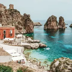 A picturesque cove with turquoise waters, rocky islets, and a charming village, this is a must-see among top places to visit in Sicily.