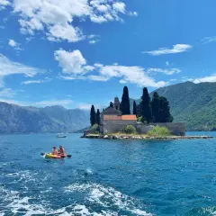 Kayaking in Montenegro's Bay of Kotor, a perfect spot for any trip planner. Mountains and a church on an island create a stunning backdrop.