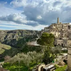 Ancient cave dwellings and a bell tower rise from a hillside in Matera, Italy. Explore this historic city for unique things to do.