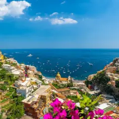 Colorful houses cascade down a cliffside to the sea, a picturesque view of the Amalfi Coast, a popular destination from Naples Airport.