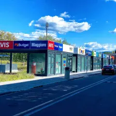 Car rental agencies like Avis, Budget, Maggiore, Hertz, and Europcar line the street, offering options for how to rent a car in Florence, Italy.