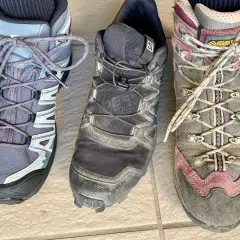 Three hiking boots: a low-cut grey boot, a mid-cut black boot, and a high-cut grey and pink boot.