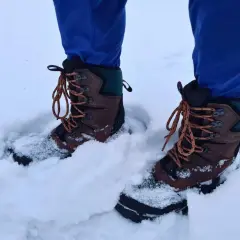 A person wearing blue pants and brown hiking boots stands in deep snow. These boots seem to be performing well, raising the question: can hiking boots be used as snow boots?