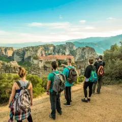 Hikers admire the stunning monasteries of Meteora, Greece, from a scenic viewpoint. The group enjoys a breathtaking vista during their hiking adventure.
