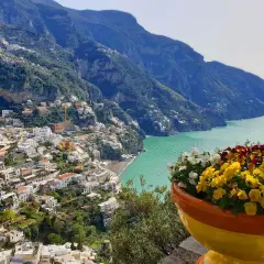 Colorful flowers bloom overlooking Positano, a stunning town cascading down the cliffs. This view offers inspiration for where to stay in Amalfi Coast.