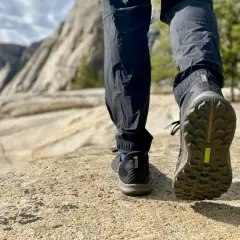 Close-up of a hiker's shoe, showing the aggressive shoe tread pattern designed for grip on rocky terrain.