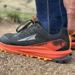Close-up of a black Altra Lone Peak 9 trail running shoe with orange accents, ready for adventure.