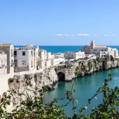 A picturesque coastal town in southern Italy, perfect for a southern Italy itinerary. White buildings cling to cliffs overlooking the turquoise sea.