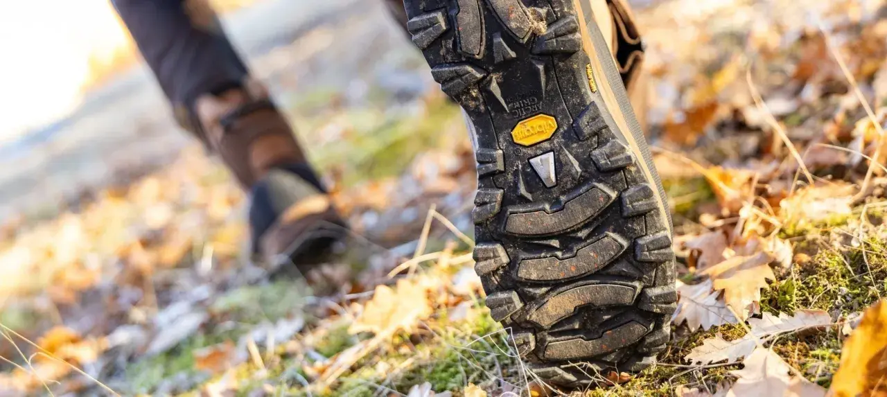 Close-up of a hiking boot sole on a forest floor. Learn how to break in hiking boots for comfortable adventures.