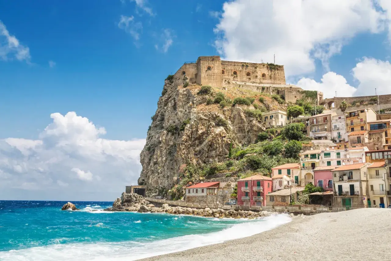 A picturesque coastal village with colorful houses clinging to a cliff, topped by an ancient castle. This is a must-see destination for anyone wondering where to go in Calabria.
