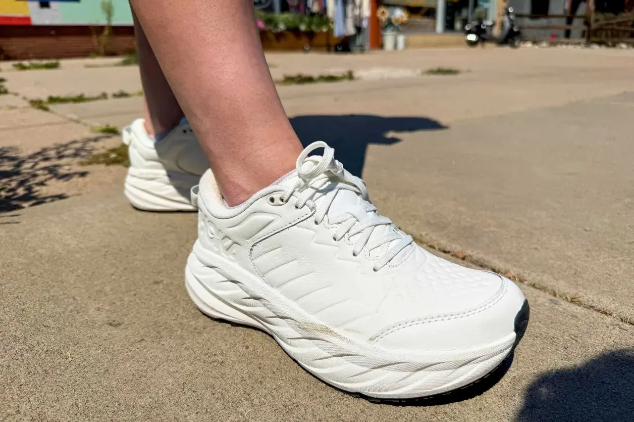 White walking shoes on a sidewalk. The question of whether walking shoes should be a size bigger is on many minds.
