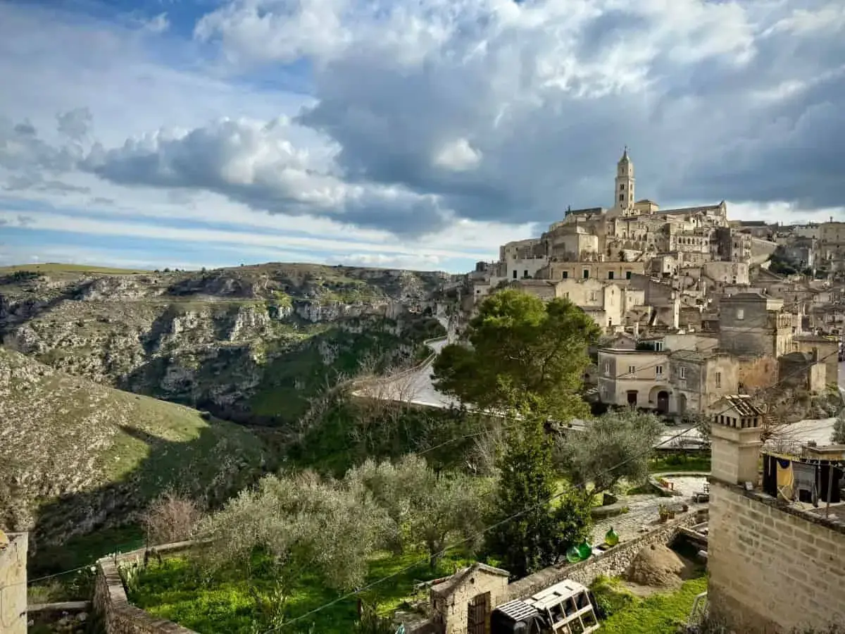 Ancient cave dwellings and a bell tower rise from a hillside in Matera, Italy. Explore this historic city for unique things to do.