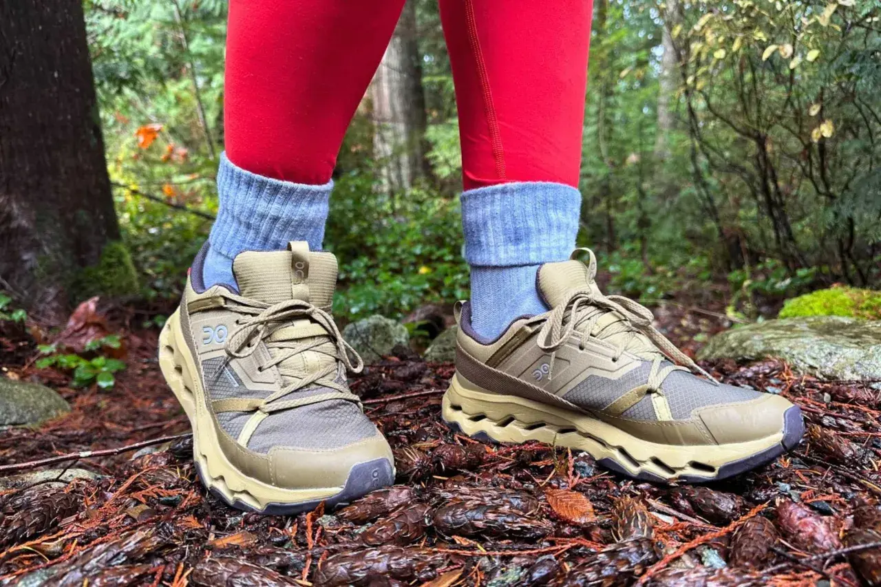 These tan hiking shoes with grey socks and red leggings are perfect for exploring a forest floor covered in pinecones.