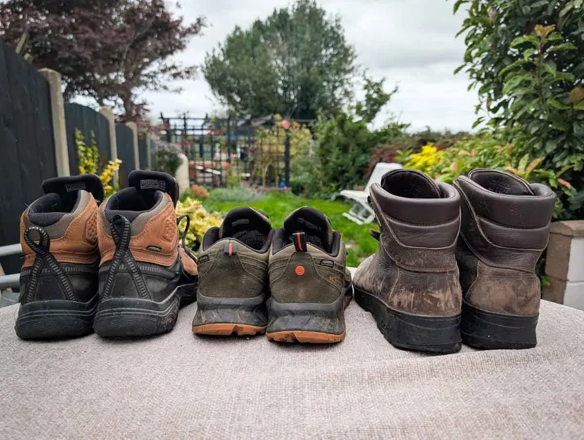 Choosing hiking boots: A selection of hiking boots and shoes, from lighter trail runners to sturdy leather boots, are lined up outdoors.