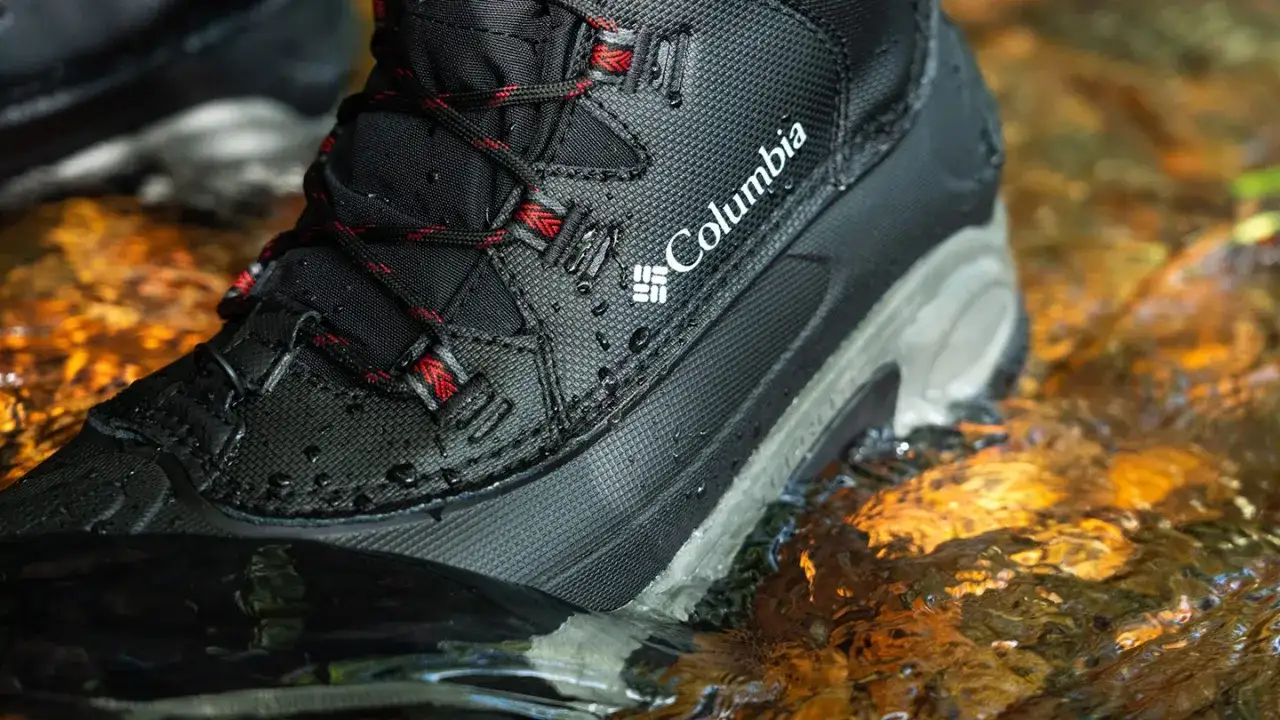 A Columbia winter boot is tested in shallow water, showing its waterproof features. Learn how to choose winter boots for your adventures.