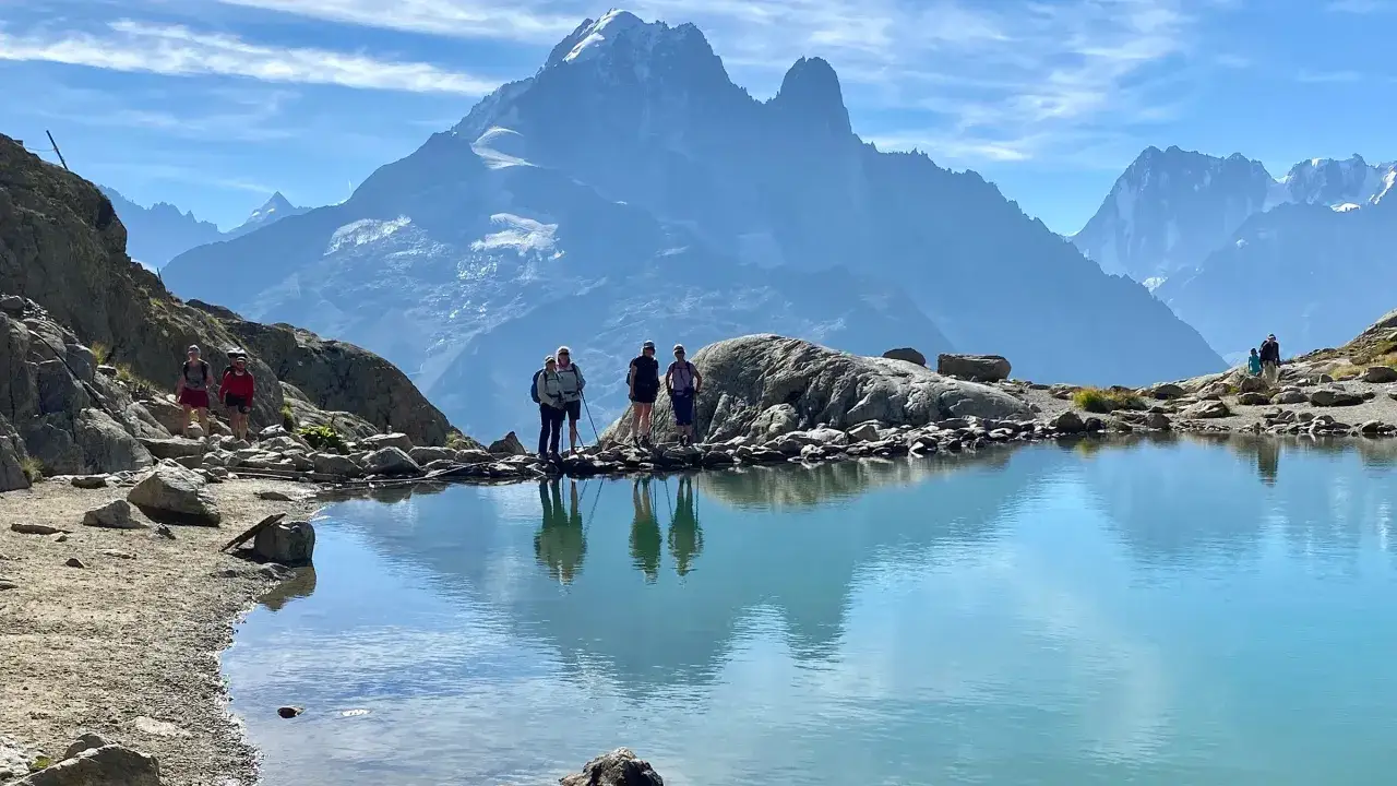 Hikers enjoy a stunning view of Mont Blanc during their tour mont blanc hike, reflected in a clear alpine lake.