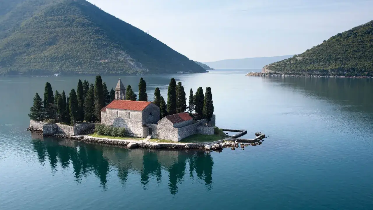 Island church with cypress trees, a perfect spot to plan a trip to Montenegro.
