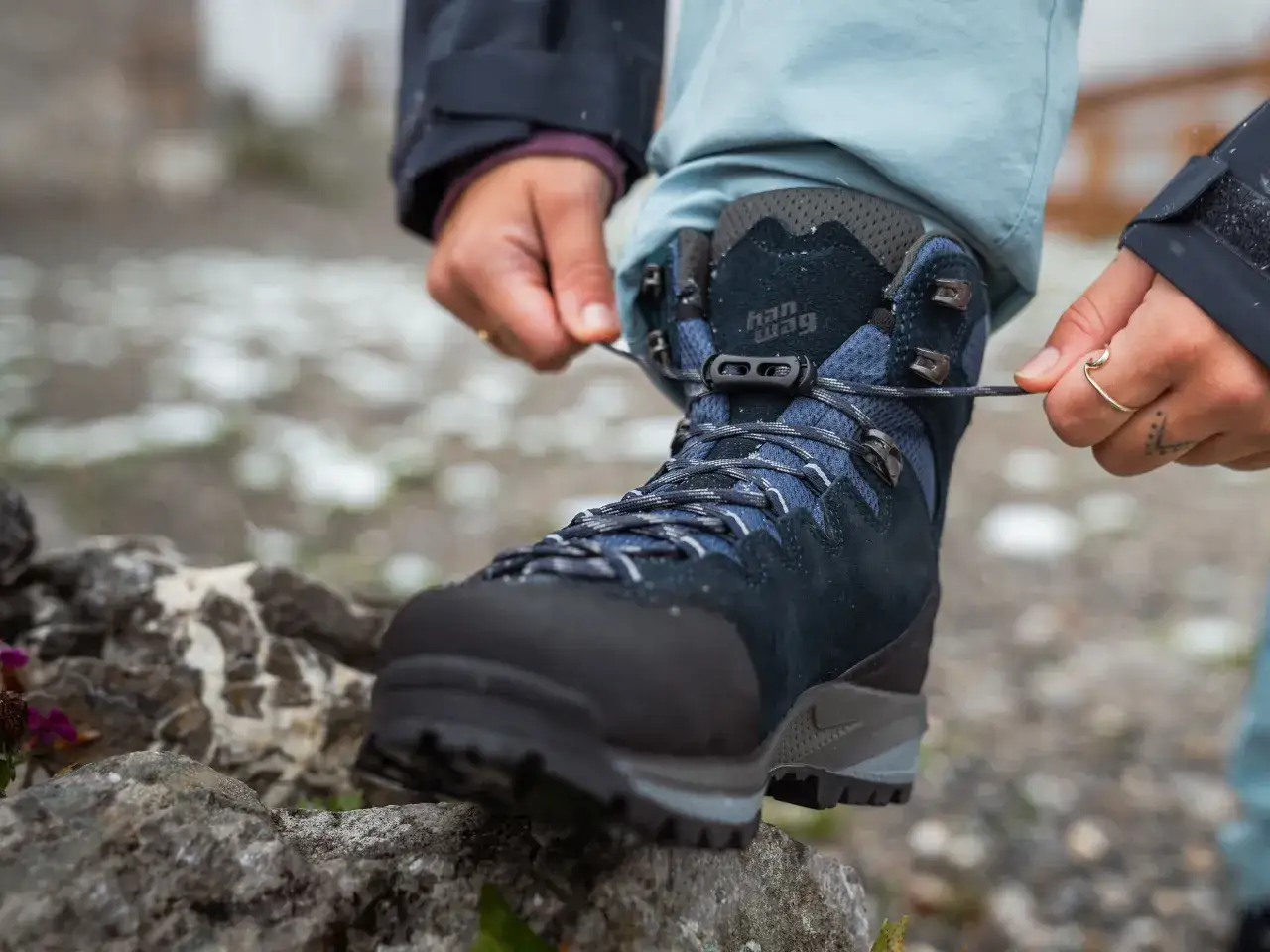 Hands tying laces on new hiking boots, a crucial step in how to break in hiking boots for comfortable adventures.