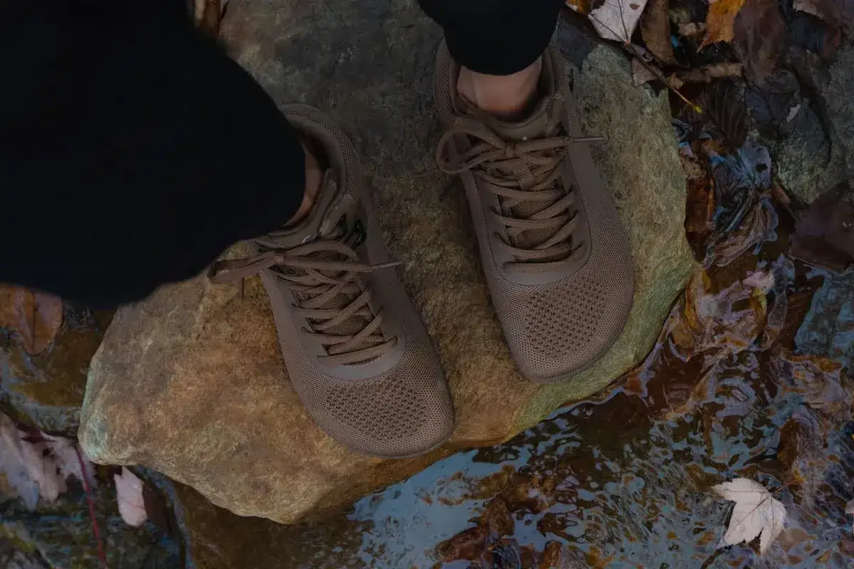 Brown hiking shoes on a rock near water. Considering if you should size up in hiking shoes? These look like they fit well.