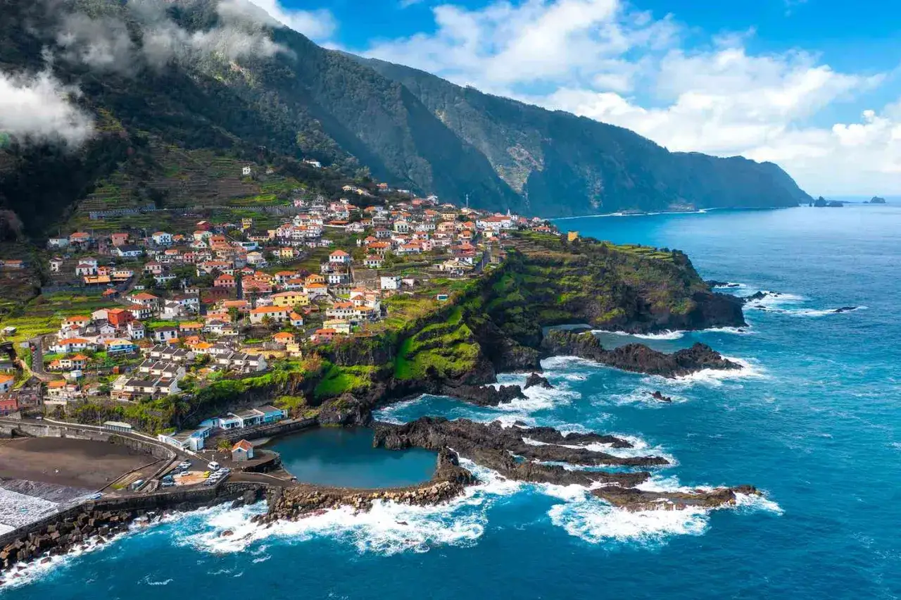 A charming village clings to a steep, terraced hillside overlooking the Atlantic. This view captures the essence of a week in Madeira, with its colorful houses and dramatic coastline.