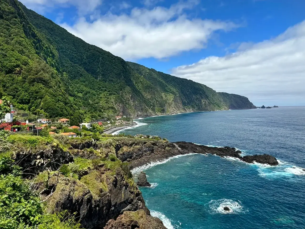 Coastal village nestled against lush green mountains, with dramatic cliffs and turquoise waters. Perfect for exploring the amazing things to do in Madeira.