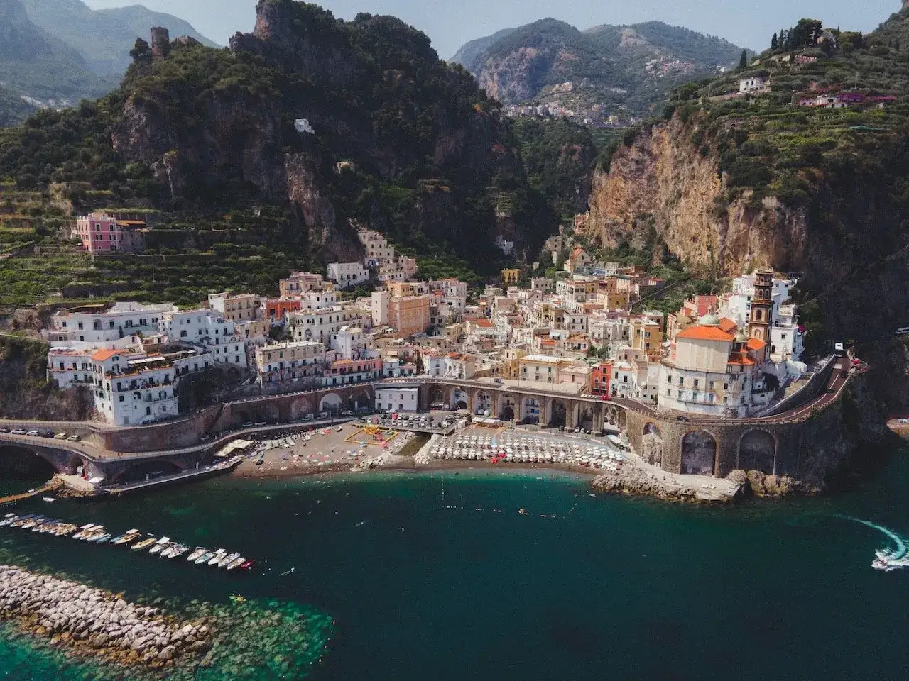 Atrani, Italy map: A picturesque coastal town nestled in a dramatic cliffside landscape. White buildings cascade down to a beach and harbor.