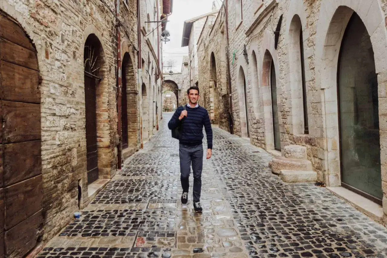 A man walks down a cobblestone alley in Orvieto, Italy, on his journey to Rome.