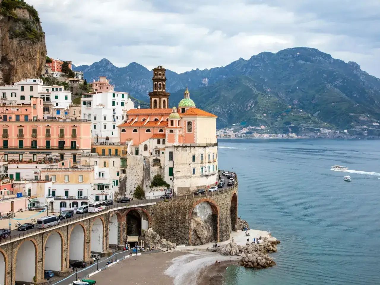 Atrani, Italy map view: colorful buildings cling to a cliffside overlooking the sea, with a historic church and a coastal road.