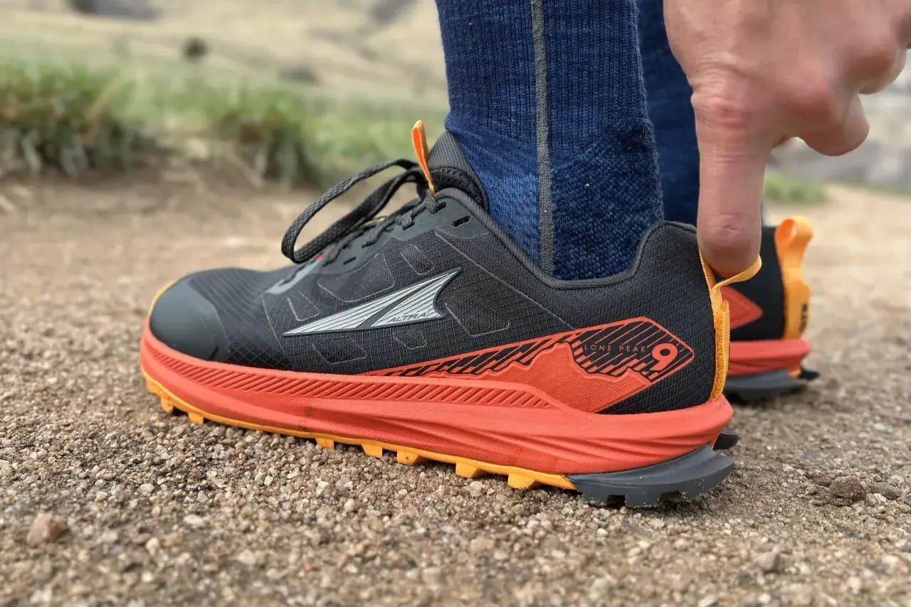 Close-up of a black Altra Lone Peak 9 trail running shoe with orange accents, ready for adventure.